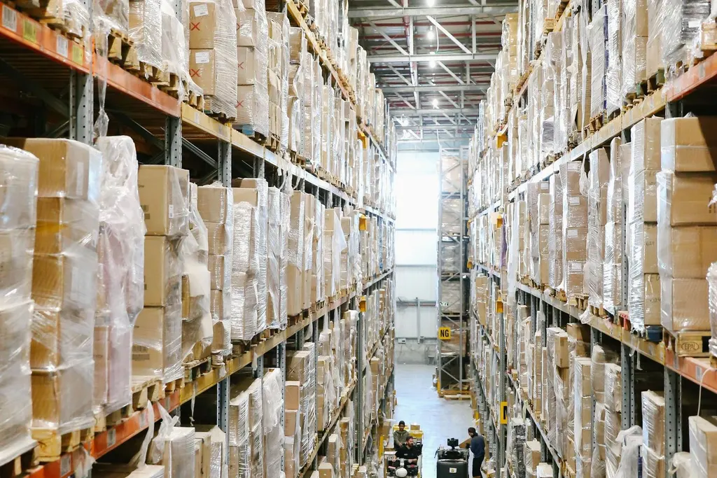 Pasillo de un almacén de distribución con estanterías llenas de cajas y palés