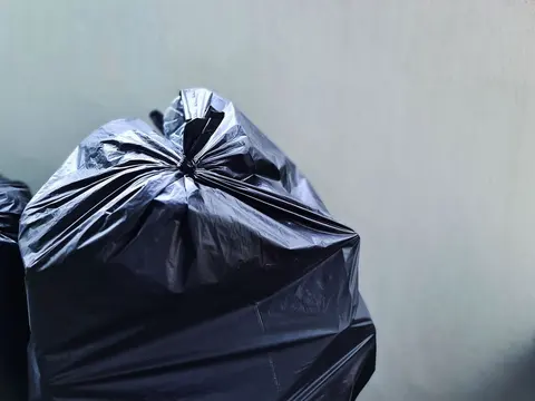 Bolsa de basura negra cerrada junto a una pared