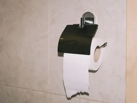 Rollo de papel higiénico en un portarrollos de acero en un baño alicatado